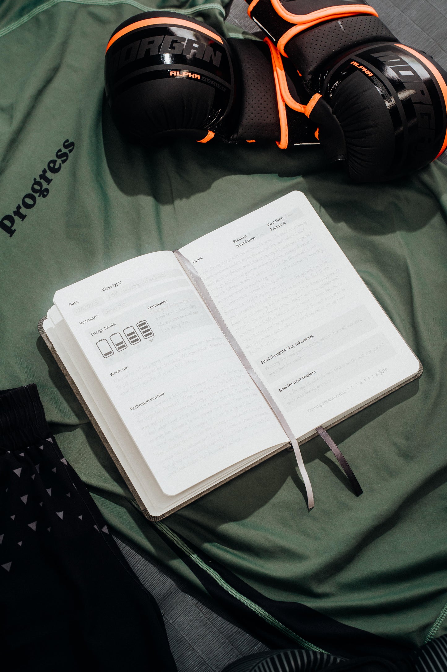 Open notebook with app icons on a green surface with boxing gloves in the background.