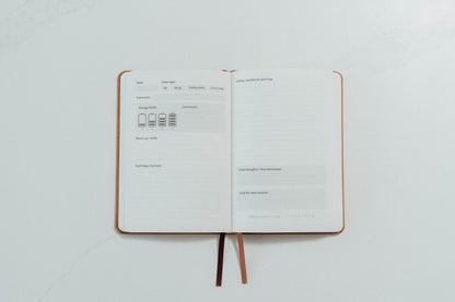 Open notebook with ivory pages and prompts to complete on a light grey background