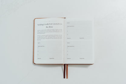 Open notebook with ivory pages and prompts relating to goals to complete on a light grey background