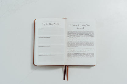 Open notebook with ivory pages and prompts to complete on a light grey background