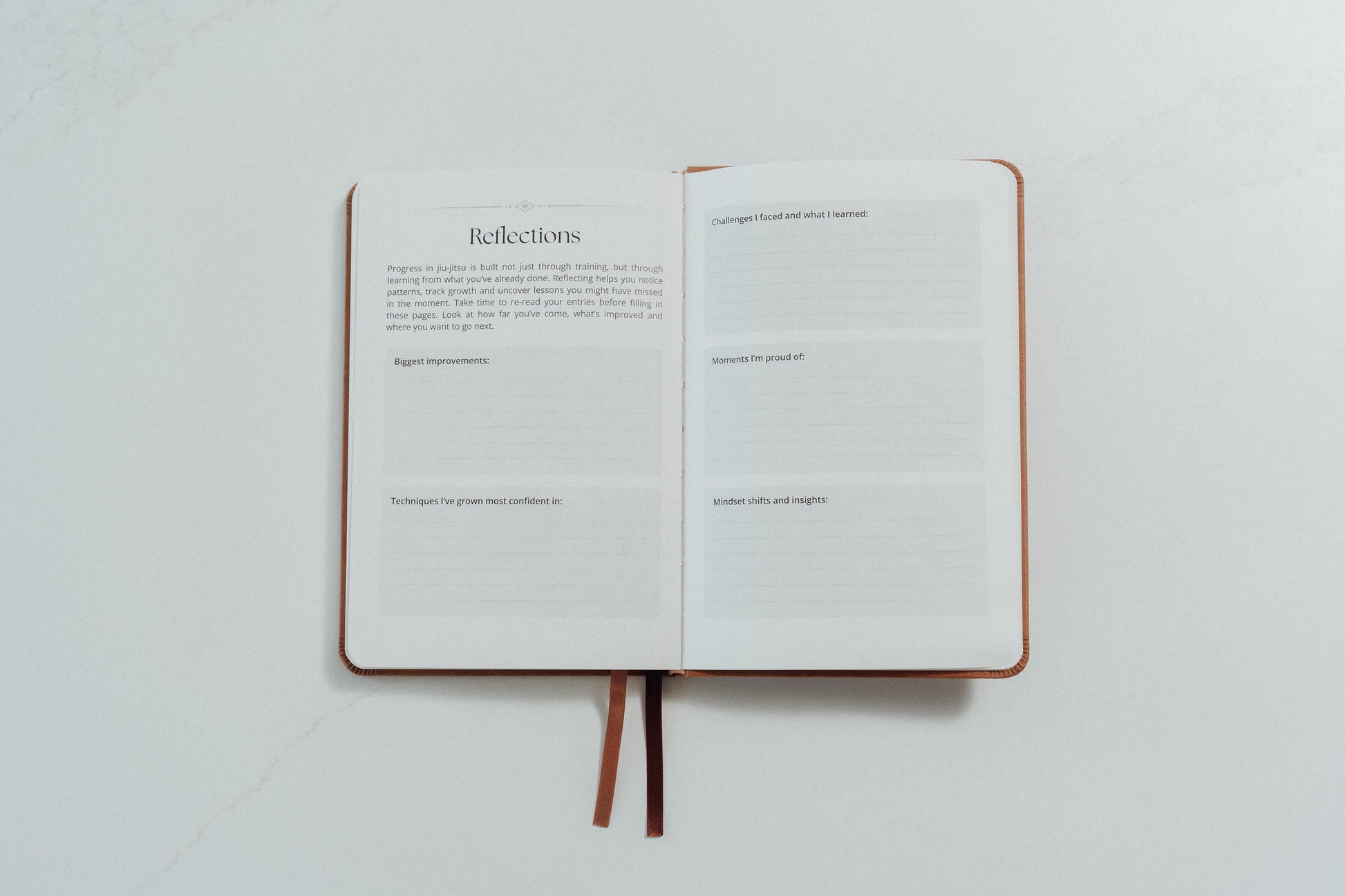 Open notebook with ivory pages and reflection prompts to complete on a light grey background