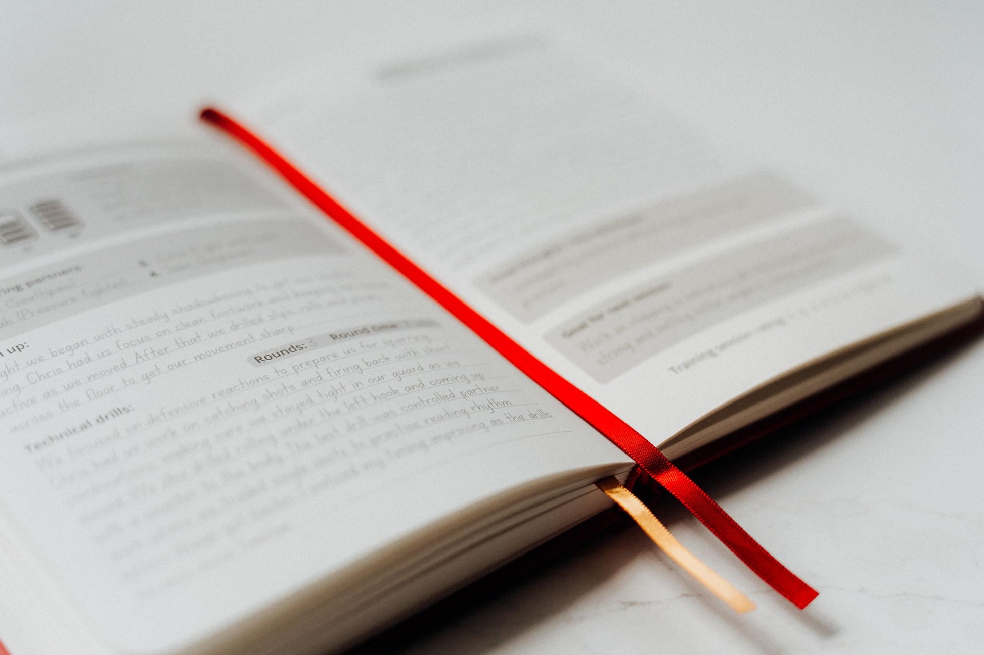 Open book with a red ribbon on a white surface