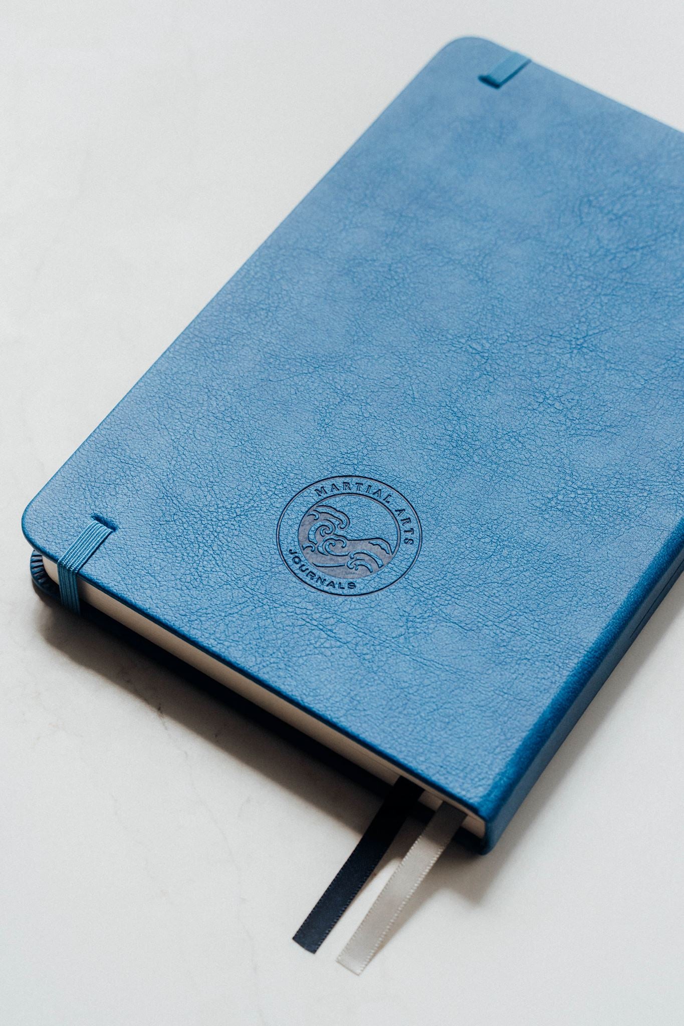 Blue notebook with a brand logo on a light grey background