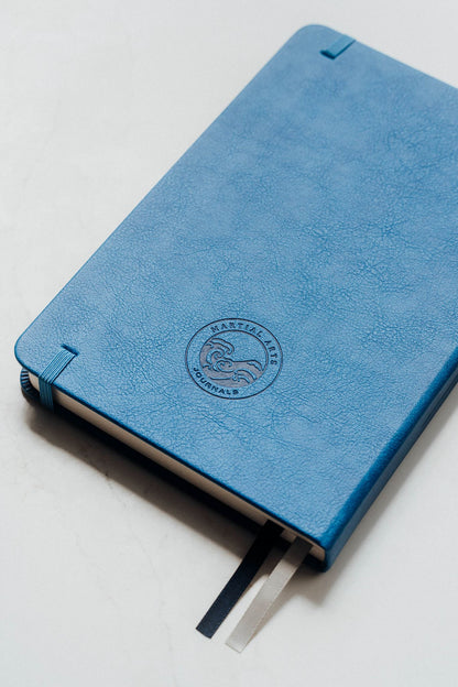 Blue notebook with a brand logo on a light grey background