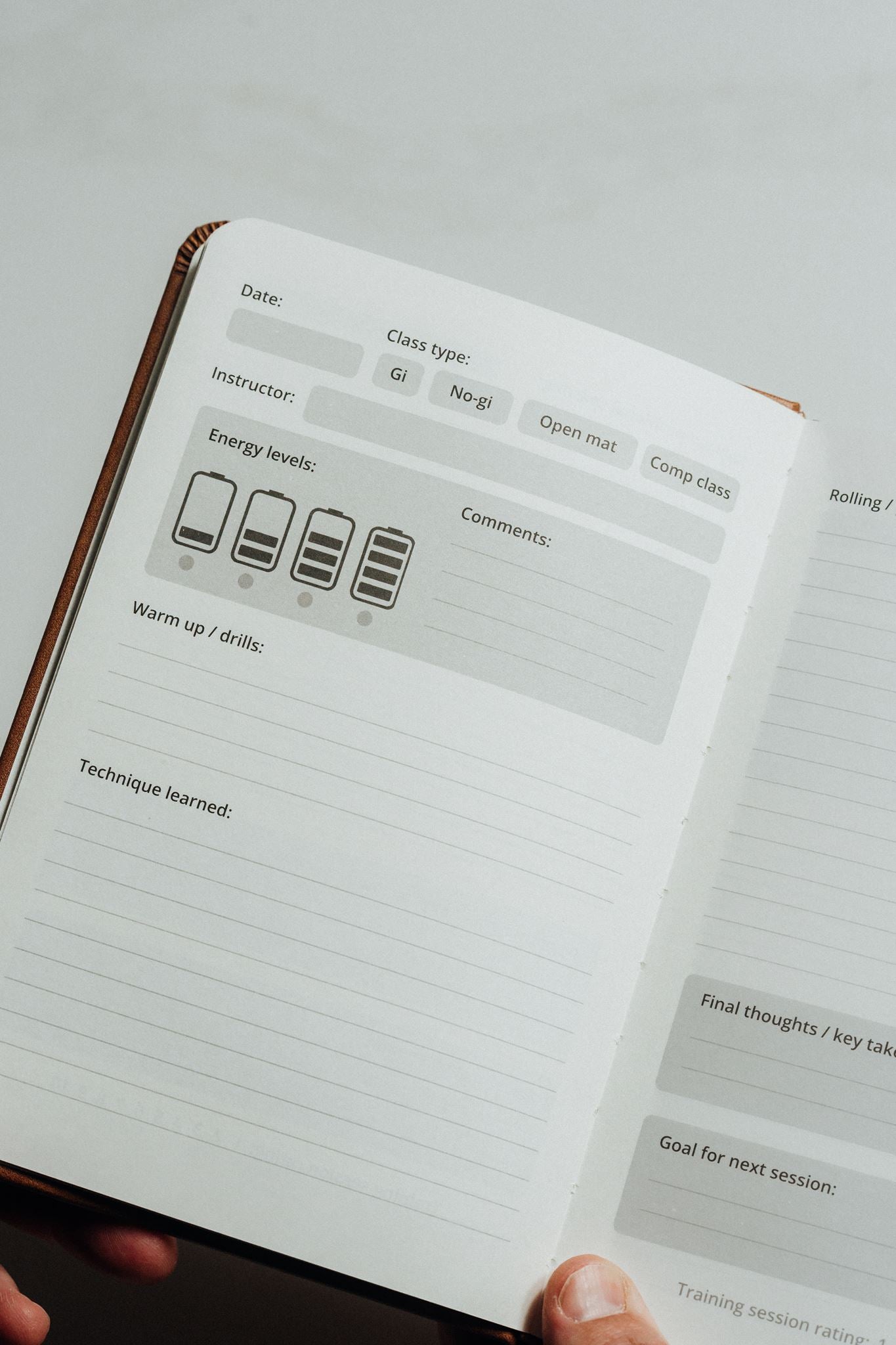 An open planner or notebook with lined pages and printed lesson-plan sections. Maint left page for bjj journal