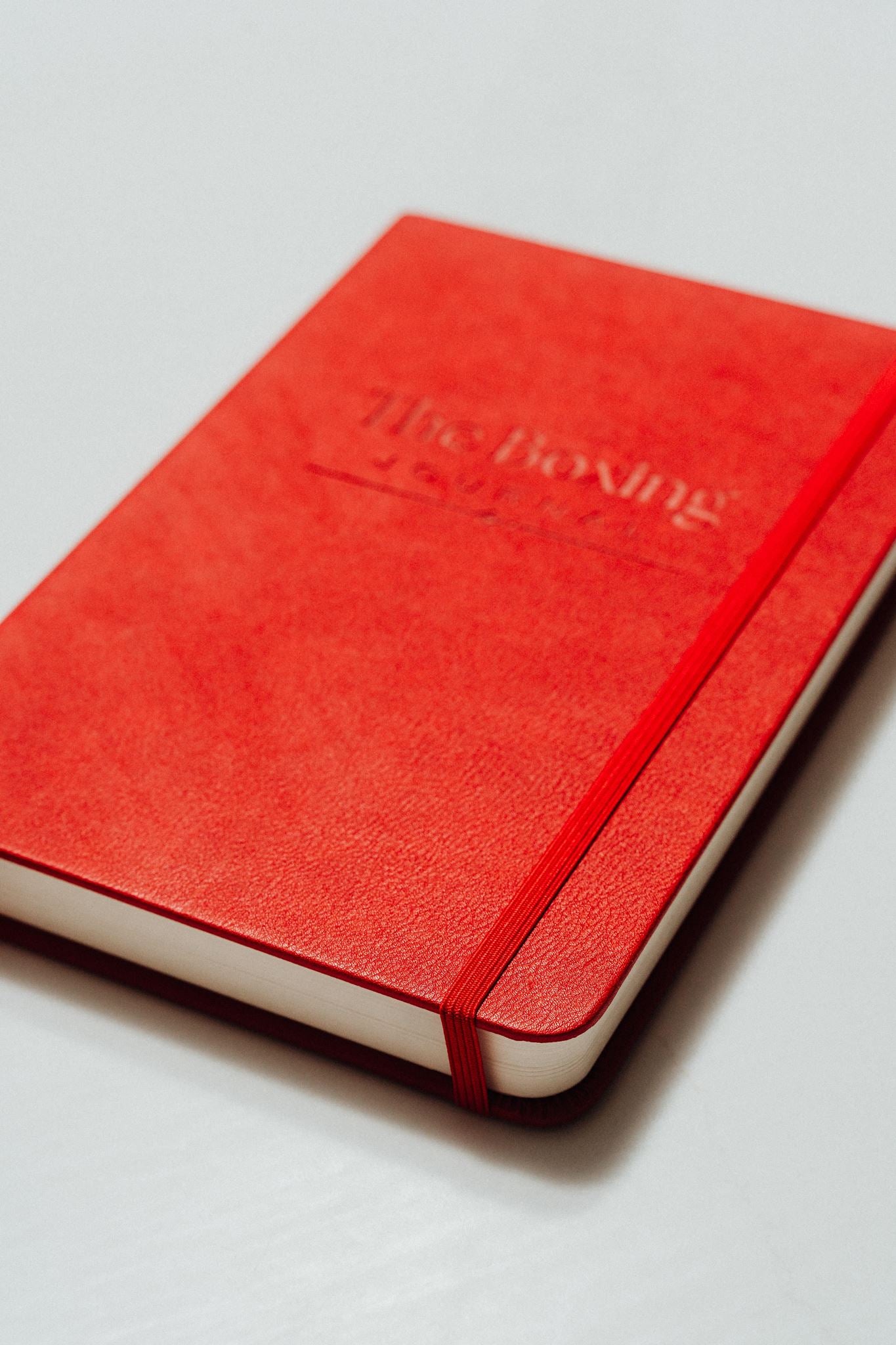 Red notebook with 'The Boxing Journal' debossed on the cover, on a light grey background