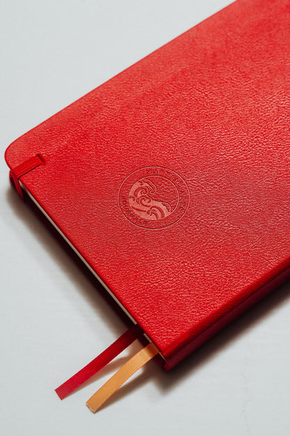 Red notebook with a logo on a light grey background