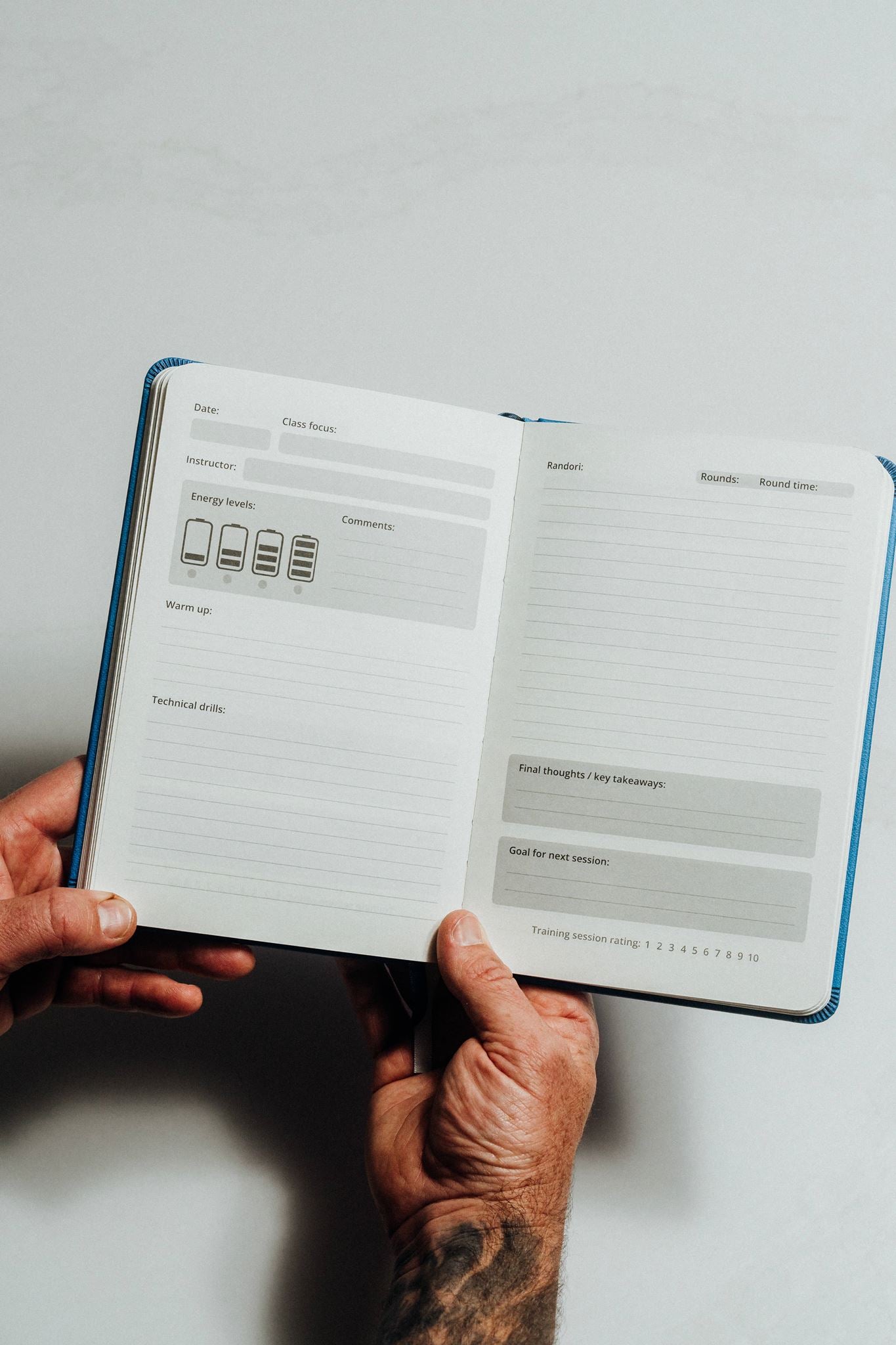 Person holding an open notebook with a minimalistic design on a light grey background