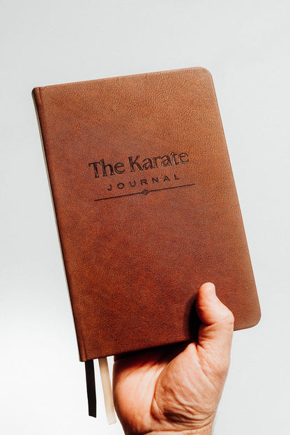 The Karate Journal held in hand showing the debossed title on the rich brown cover
