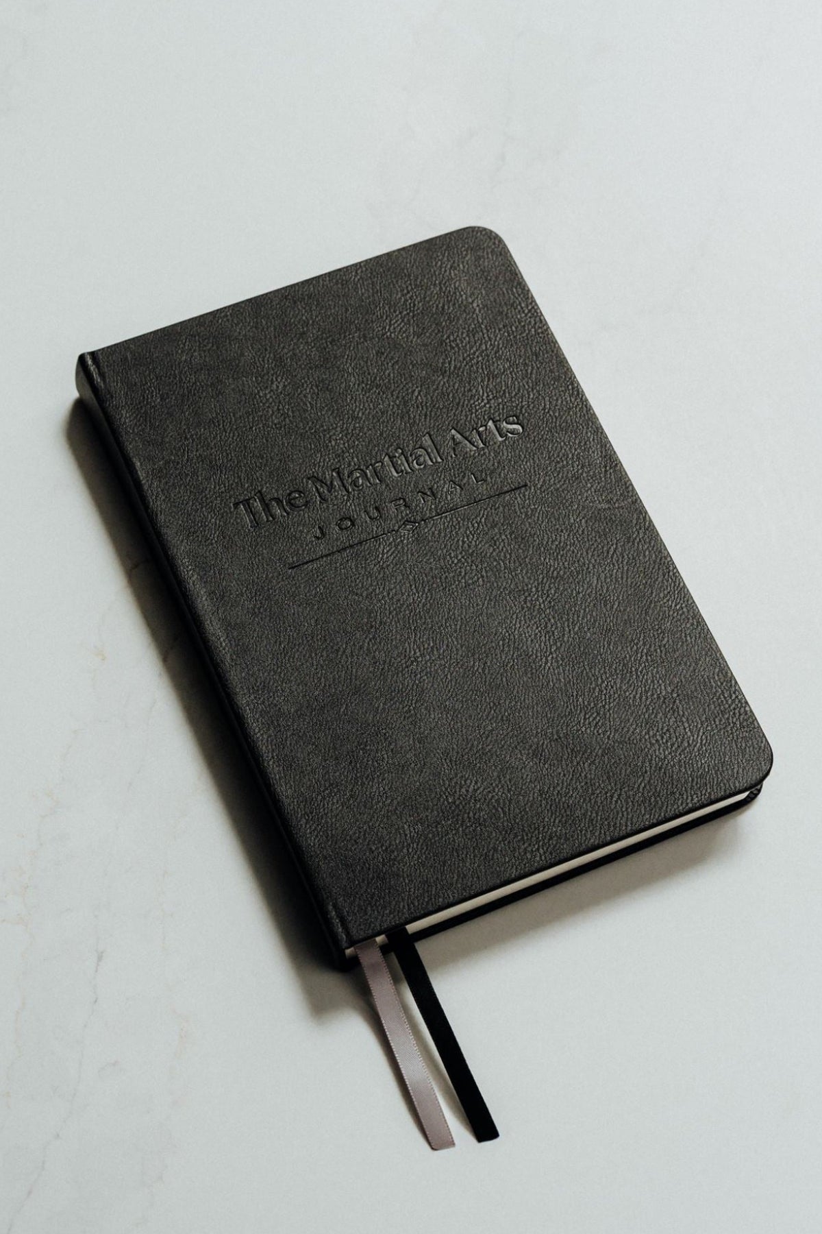 The martial arts journal in black set on a white background with debossed logo