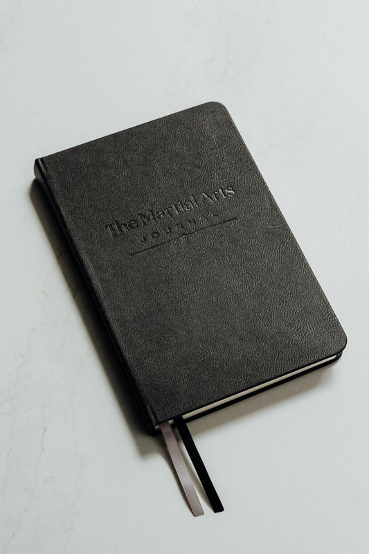 The martial arts journal in black set on a white background with debossed logo